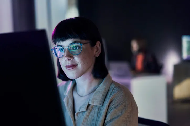 Business-Frau, Codierung durch eine junge Mitarbeiterin mit blauem Licht und Brille. 