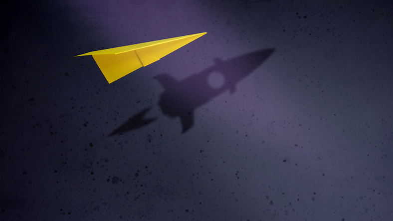 Ein Papierflieger wirft einen Schatten in Form einer Rakete.