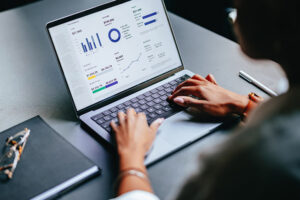 Eine Frau sieht sich grafische Darstellungen von Finanzen auf einem Laptop an