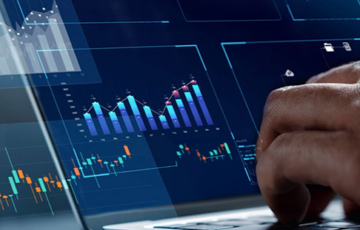 Eine Person tippt auf Laptop, man sieht verschiedene Grafiken auf dem Bildschirm