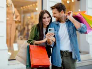 Glückliches Paar mit Einkaufstüten und Smartphone